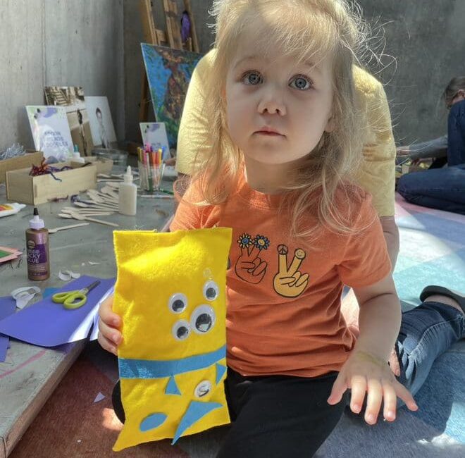 Small child holding a toy monster she made.
