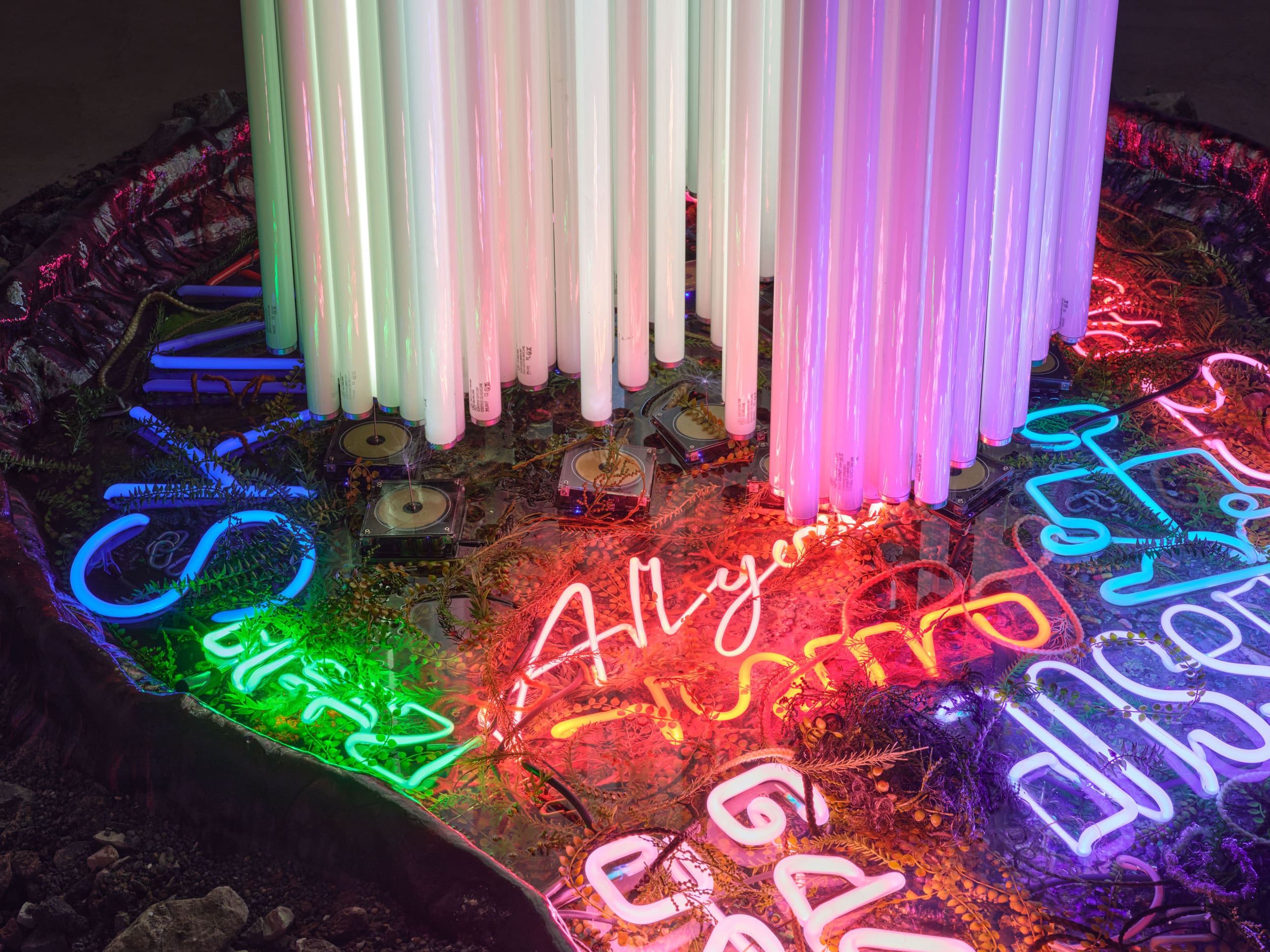 Max Hooper Schneider. Falling Angel, 2023. Aircraft wreckage, fluorescent light tubes, Tesla coils, vintage neon signs, chains, crushed concrete, mixed media fiberglass pond, microcontoller. Courtesy of the artist ©Max Hooper Schneider