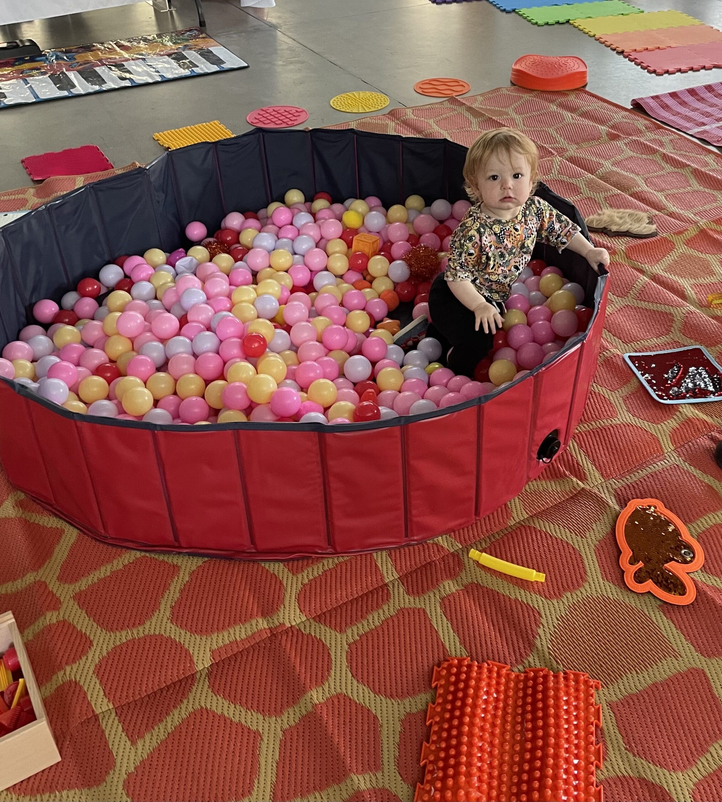 A toddler playing in a ball pit.