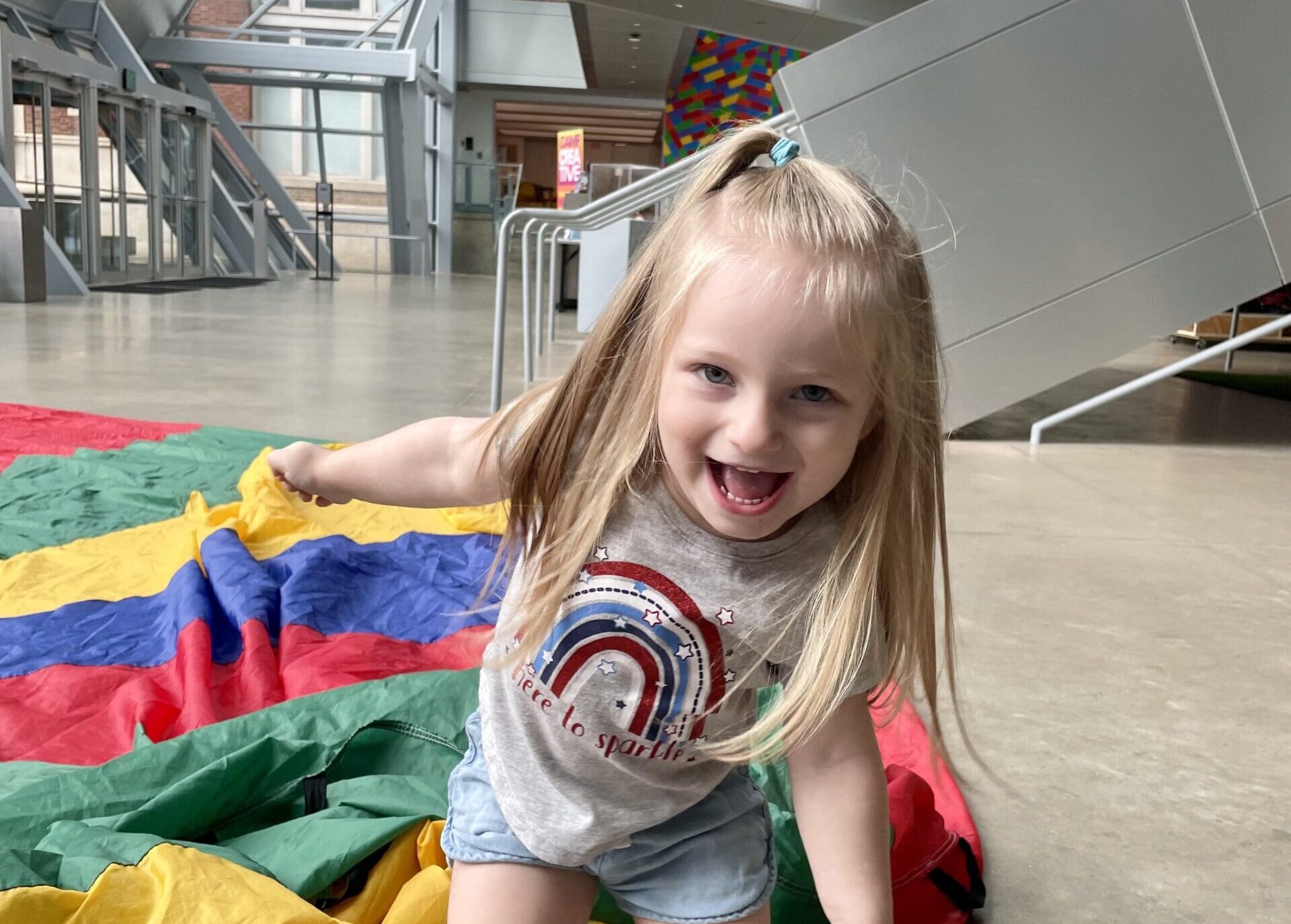 A girl playing with a folded piece of parachute fabric.