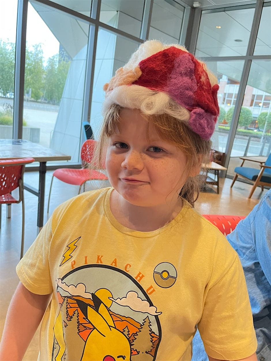 A child wearing a cozy hat made during a kids event at the Akron Art Museum